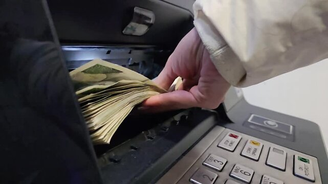 Woman inserting stack of cash into ATM deposit slot during banking transaction. Close-up of hands holding banknotes near automated teller machine keypad, concept of finance, payment, savings and banki