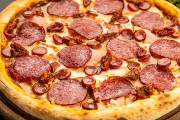 Fresh pepperoni pizza on wooden board with salami, sausage and spices, top view