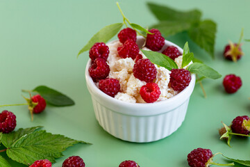 Healthy cottage cheese with raspberries and green leaves on the background