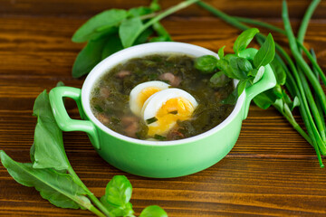 Traditional Ukrainian sorrel borscht with egg on dark wooden table