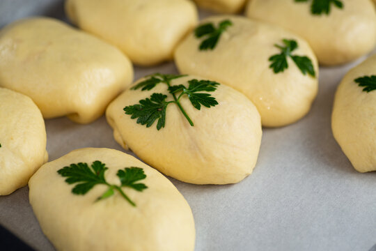 Unbaked dough pieces decorated with parsley ready for oven