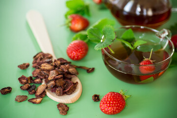 Bright strawberry tea in transparent glassware on a green background