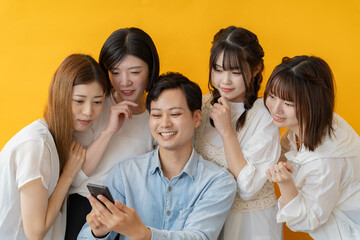 スマホ画面を囲んで楽しむ若者グループの笑顔の瞬間