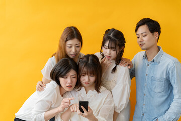 Obraz premium スマホ画面を囲んで楽しむ若者グループの笑顔の瞬間