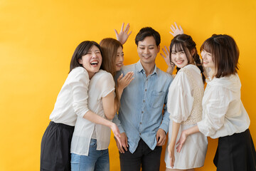 黄色い背景で笑顔ではしゃぐ友人グループ