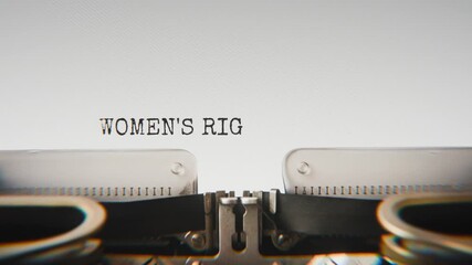 Old mechanical typewriter typing Women's Rights in a close-up view, with metal letters striking the white paper. - Powered by Adobe