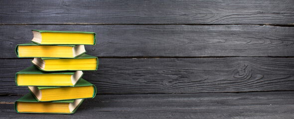 Books on wooden table, black board background. Back to school. Education business concept. panorama, banner.