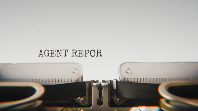 Old mechanical typewriter typing Agent Report 9b in a close-up view, with metal letters striking the white paper.