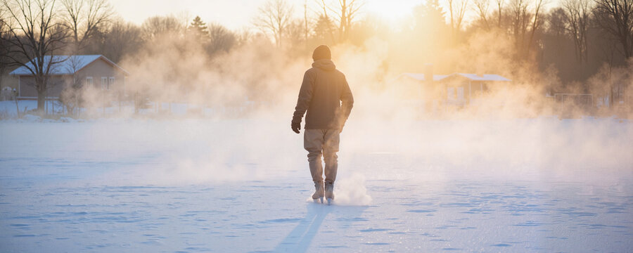 Man walking in snowy landscape during sunset in winter  