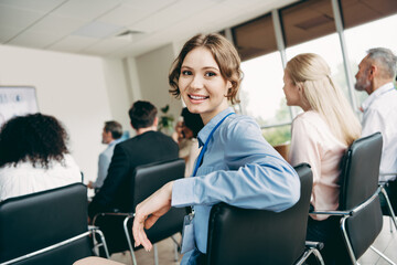 Obraz premium Young businesswoman attending a professional development conference with a team of professionals in an office setting