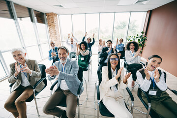Diverse group of professionals applauding at a corporate training event held in a modern office setting
