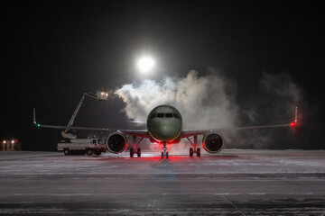 Ground deicing of a passenger jetliner on the night airport at winter
