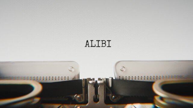 Old mechanical typewriter typing Alibi in a close-up view, with metal letters striking the white paper.