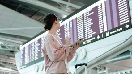 A young woman stands in a modern airport terminal, checking her smartphone, surrounded by departure information boards and a spacious waiting area, expressing anticipation and excitement about the jou - Powered by Adobe