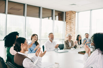 Diverse office team collaborating in a modern conference room, enthusiastically applauding after a successful discussion or presentation