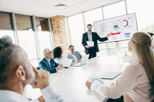 Professional teamwork and collaboration in a corporate meeting with a leader presenting on a large office screen - Powered by Adobe
