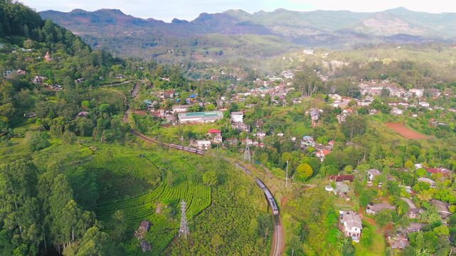 Scenic Drone View of Train Approaching Rural Town Across Lush Green Landscape