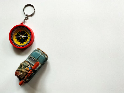 A small blue toy car and compass. The arrangement evokes a travel theme.
