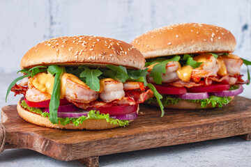 Shrimp burgers with fresh ingredients are served on a wooden board in a bright kitchen,