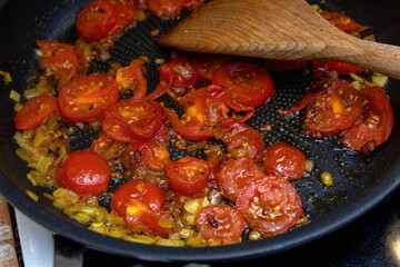 Fresh tomatoes and onion cooking in skillet.