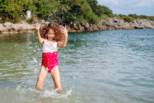 Red-haired girl playing in the water on a beach on the Brazilian coast, in the city of Bombinhas, Santa Catarina.