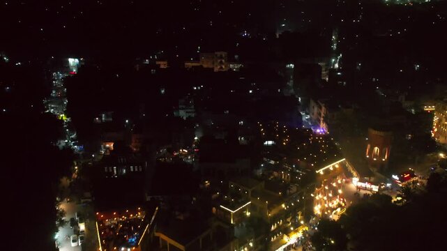 Aerial view of a vibrant city glowing with warm light against the dark night, illuminating buildings and streets, lights creating an inviting atmosphere, Murree, Punjab, Pakistan.