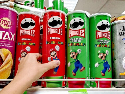 Belarus, Svetlogorsk, September 10, 2025. Customer's hand pointing at limited-edition Pringles cans with Super Mario design (Mario and Luigi) on supermarket shelf among classic flavors.