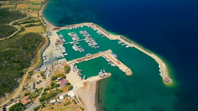 Aerial view of Kormen Marina showcasing boats docked in the turquoise waters, juxtaposed against the dark blue sea, Datca, Mugla, Turkiye.