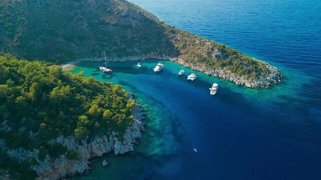 Aerial view of boats nestled in Mersincik bay, where turquoise waters meet the rugged, green coastline, creating a stunning contrast of colors, Datca, Mugla, Turkiye.