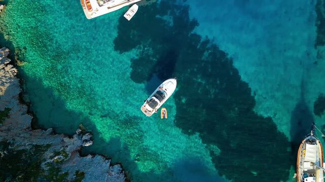 Aerial view of boats floating on the turquoise waters of Mersincik Bay, contrasting with the rocky coastline, creating a stunning seascape, Datca, Mugla, Turkiye.