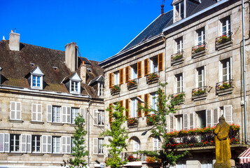 Picturesque traditional stone buildings, typical of a French town, with white shutters and flower boxes