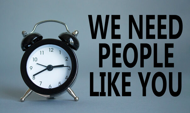 Hiring symbol. Wooden blocks with words We need People like You. Beautiful grey background with alarm clock. Business and Hiring concept. Copy space.