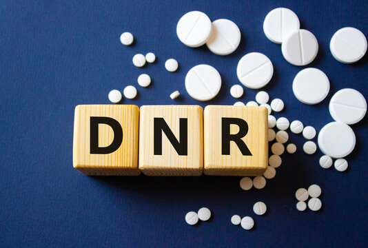 DNR symbol. Wooden cubes with words DNR Do not resuscitate. Beautiful deep blue background. Healthcare and Do not resuscitate concept. Copy space.