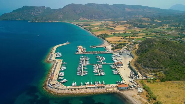 Aerial view of Kormen Marina, where turquoise waters meet lush green hills and docked boats create a vibrant tapestry of color, Datca, Mugla, Turkiye.