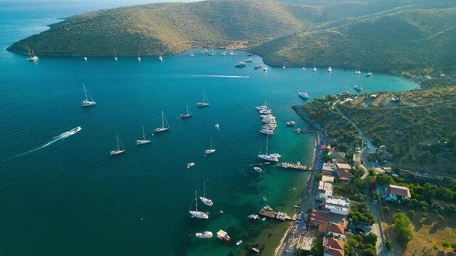 Aerial view of boats sailing on the turquoise sea, contrasting with the rugged coastline and hills, creating a serene seascape, Cokertme, Mugla, Turkiye.