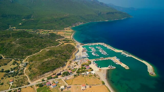 Aerial view of boats docked in Kormen Marina, the turquoise water contrasts with the lush green landscape, creating a beautiful scene, Datca, Mugla, Turkiye.