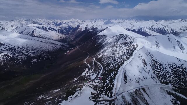 Aerial view of snow-dusted mountains, as a winding road carves through the peaks, revealing a breathtaking vista of Babusar Pass, Naran, Khyber Pakhtonkhawa, Pakistan.