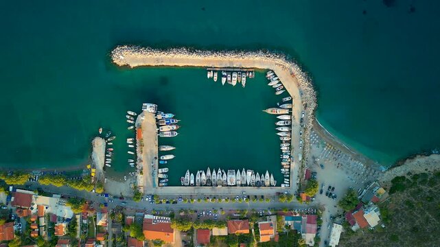 Aerial view of boats docked at Palamutbuku harbor, with turquoise waters contrasting against the light sandy beach, Palamutbuku, Datca, Turkiye.