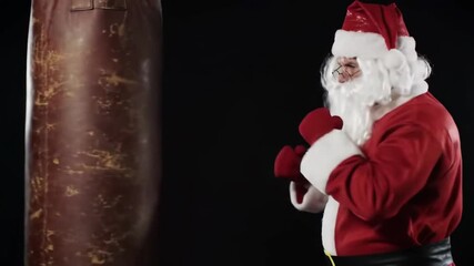 Santa in boxing gloves, punching bag, black background, humorous Christmas card use