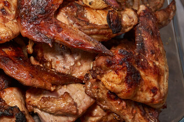 Juicy pieces of chicken were grilled in a metal grill over hot coals. The ruddy crust and smoky aroma emphasize the atmosphere of a picnic and a summer vacation in nature.