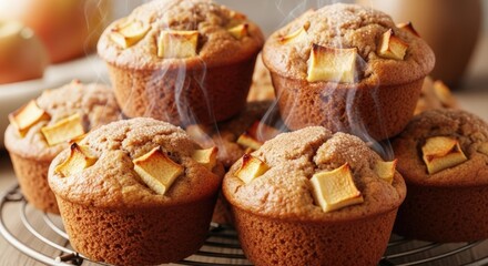 Warm, freshly baked apple muffins with visible apple chunks on a cooling rack, emitting steam.