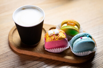 Colorful desserts and a cup of coffee on a wooden tray