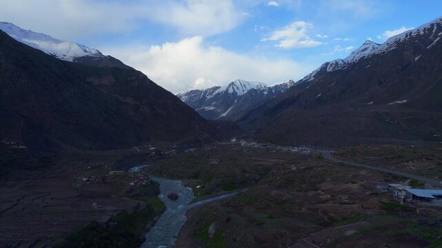 Aerial view of a river flowing through a valley between majestic mountains, their peaks capped with snow, Naran, Khyber Pakhtunkhwa, Pakistan.