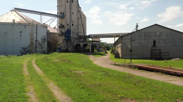 Cincinnati, United States - 02 August 2025: Aerial view of weathered silos and a long, low building connected by a metal walkway, surrounded by green grass.