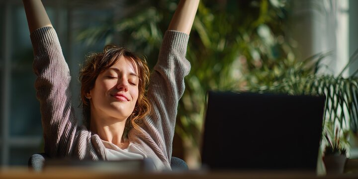 Woman enjoying a moment of relaxation at her workspace in a bright room filled with plants during a sunny day