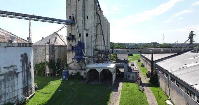 Cincinnati, United States - 02 August 2025: Aerial view of weathered grain elevators and silos stand in stark contrast to the verdant green grass below.