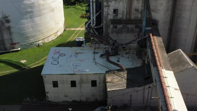 Cincinnati, United States - 02 August 2025: Aerial view of tall, weathered industrial silos casting shadows, their cylindrical forms a stark contrast against the green landscape.