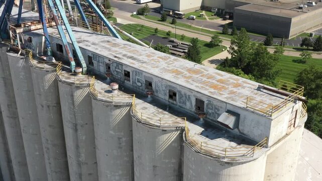 Cincinnati, United States - 02 August 2025: Aerial view of weathered concrete silos stand tall, adorned with graffiti, contrasting against the lush greenery.