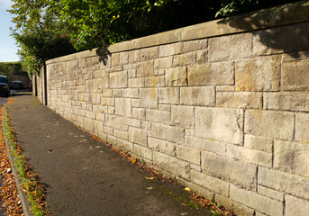 Stone wall catching sunshine, and pavement, outside garden, in the Victorian suburb of Morningside, Edinburgh, Scotland, UK