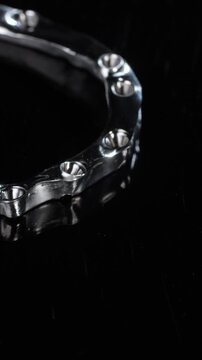 Titanium dental framework shows curved arch and joint elements against deep black. Shaped metal follows tooth line while precise edges support implant connection vertical video